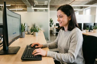 Femme utilisant un clavier ergonomique split dans un open space moderne avec bureau double écran